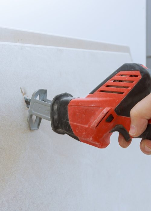 Worker cuts with a dirty saw drywall repair cutting gypsum board